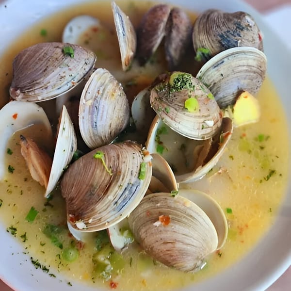 A close-up of steamed clams in a light broth with herbs, a dish from Cape Fear Café.