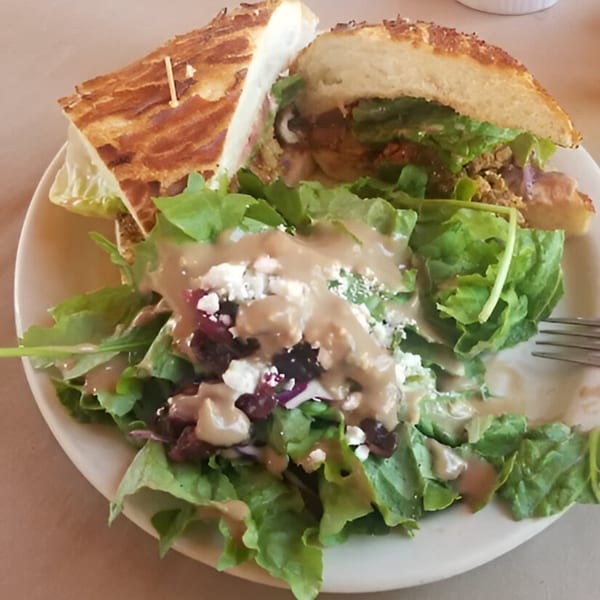 Cape Fear Café's sandwich with a side salad topped with dressing, feta, and cranberries.